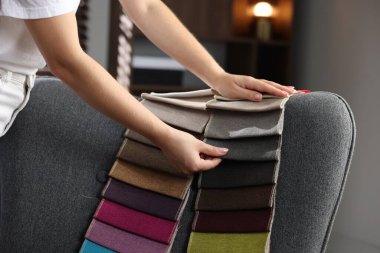 Kadın farklı örnekler arasından kumaşı seçiyor, kapalı alanda, yakın plan.