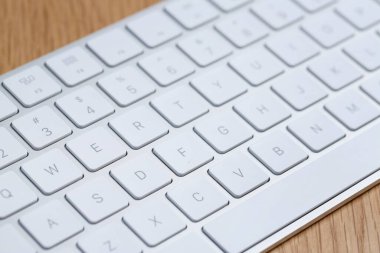 Modern beyaz kablosuz klavye ahşap masada, yakın plan