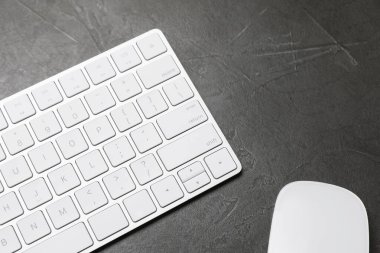 Gri masadaki modern beyaz kablosuz klavye ve fare.
