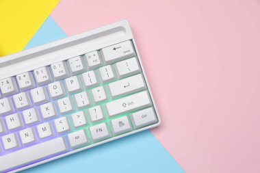Renkli arka planda RGB ışıklandırması olan modern beyaz klavye, üst görünüm. Metin için boşluk