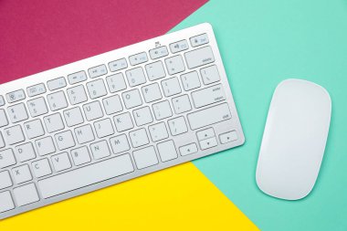 Renk arkaplanı üzerinde modern beyaz kablosuz klavye ve fare, üst görünüm