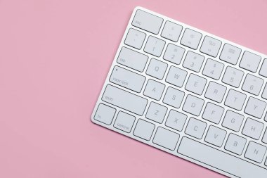 Pembe arka planda modern beyaz kablosuz klavye, üst manzara. Metin için boşluk