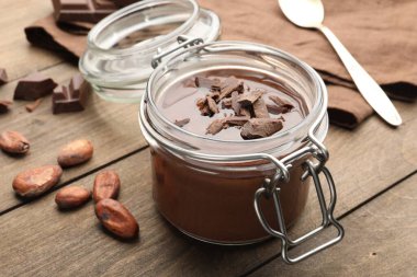 Cam kavanozda nefis çikolata panna cotta, ahşap masada fındık ve kaşık, yakın plan.