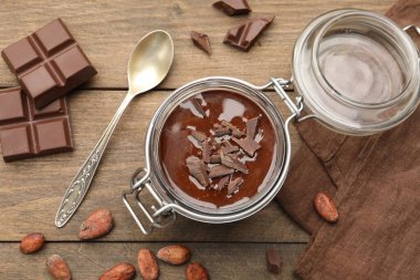 Cam kavanozda nefis çikolatalı panna cotta, ahşap masada fındık ve kaşık, düz uzanmış