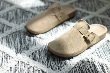 Yumuşak halıda şık bej terlikler, yakın plan.