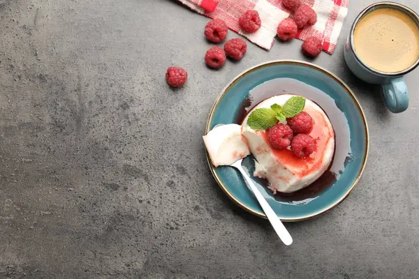 Lezzetli panna cotta, böğürtlen, sos ve nane şekerli gri desenli masa, düz yatak. Metin için boşluk
