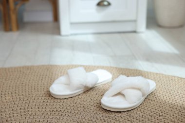 Pofuduk beyaz terlikler hasır paspasın üzerinde, yakın plan.