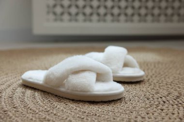 Pofuduk beyaz terlikler hasır paspasın üzerinde, yakın plan.