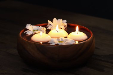 Mumları yakıyor, çiçekleri suyla dolduruyor, ahşap masada, yakın plan.