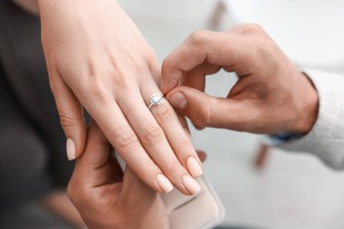 Evlenme teklif ediyorum. Erkek, kız arkadaşının parmağına nişan yüzüğü takar.