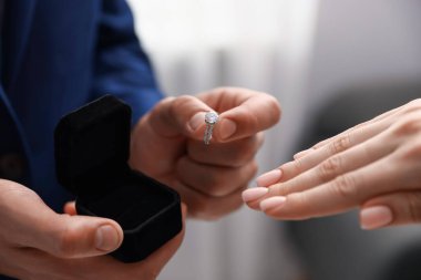 Nişan yüzüklü bir adam içeride kız arkadaşına evlenme teklif ediyor.