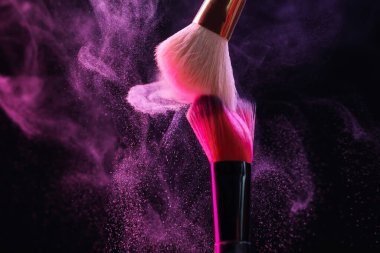 Renkli göz gölgeli makyaj fırçaları siyah arka planda neon ışıkları, yakın plan