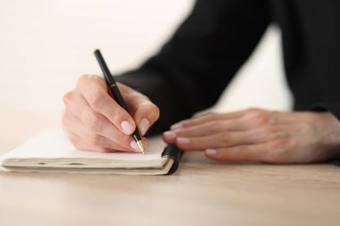 Kalemle tahta masada arka planda yazan kadın, yakın plan.