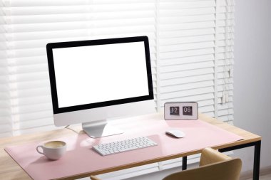 İçerideki ahşap masada bilgisayar ve pembe fare altlığı olan şık bir iş yeri. Metin için boşluk