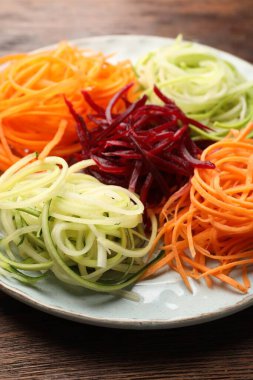 Ahşap masada farklı sebze erişteleri, yakın plan.