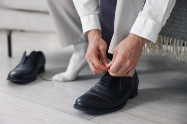 Hazırlanıyor. Genç adam evde şık ayakkabılar giyiyor, yakın plan.