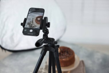 Stüdyoda akıllı telefonla çikolatalı pasta çekmek, seçici odaklanma. Profesyonel yemek fotoğrafçılığı.