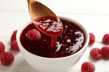 Beyaz masada kaseden kaşıkla ahududu reçeli alıp...