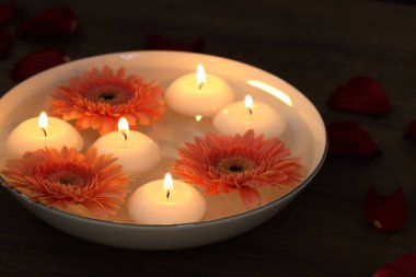 Mumları yakıyor, çiçekleri suyla dolduruyor, ahşap masada, yakın plan.