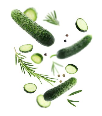 Beyaz arka plana düşen taze salatalıklar, biberiye ve biber taneleri.