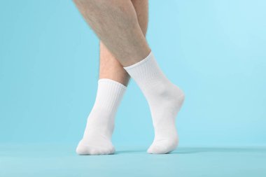 Açık mavi arka planda temiz beyaz çorap giyen adam, yakın plan.