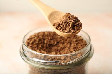 Kavanozdan granüle hazır kahveyi alıyorum. Arka planda bulanık ışık var. Yakın plan.