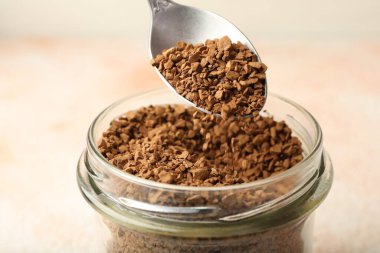 Kavanozdan granüle hazır kahveyi alıyorum. Arka planda bulanık ışık var. Yakın plan.