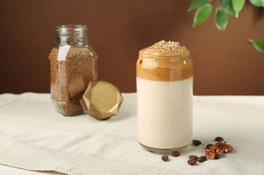 Bardakta lezzetli dalgona kahvesi, fasulye, ceviz ve granüller masada.