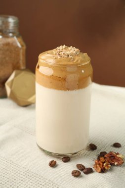 Bardakta lezzetli dalgona kahvesi, fasulye, ceviz ve granüller masada, yakın plan.