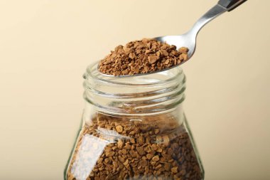 Bej arka planda kaşıkla hazır kahve içmek, yakın plan.