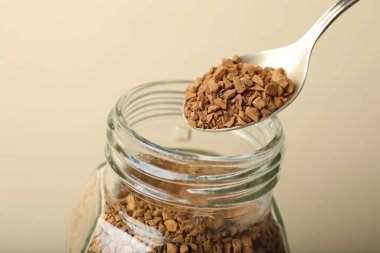 Bej arka planda kaşıkla hazır kahve içmek, yakın plan.