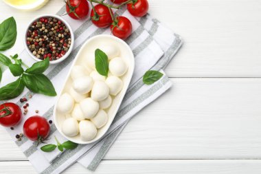 Lezzetli mozzarella peyniri, domates, fesleğen ve baharatlar beyaz ahşap masa, düz yatak. Metin için boşluk