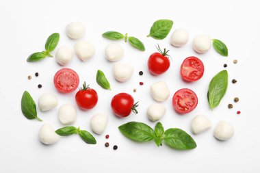 Lezzetli mozzarella peyniri topları, domatesler, fesleğen ve biberler beyaz arka planda, düz yayılmış