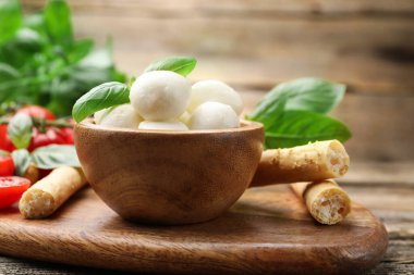 Lezzetli mozzarella peynir topları, domatesler, fesleğen ve Grissini masada, yakın plan.