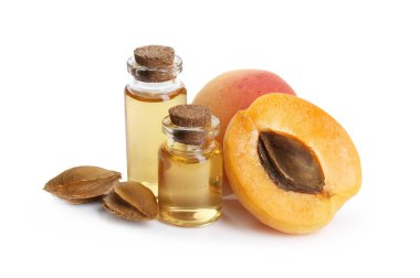 Beyaz üzerine izole edilmiş yağ, taze kayısı ve çekirdek şişeleri.