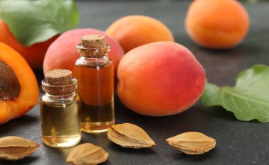 Şişelerde, tohumlarda ve olgun kayısılarda koyu dokulu masalarda, yakın çekim.