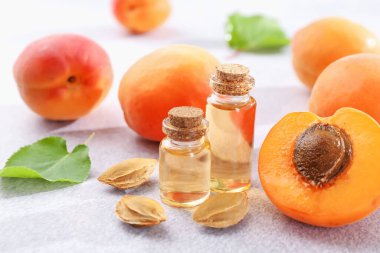 Şişelerdeki, tohumlardaki ve olgun kayısılardaki yağlar açık dokulu masalarda, yakın çekim.