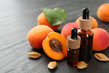 Şişelerde, tohumlarda ve olgun kayısılarda koyu dokulu masalarda, yakın çekim.