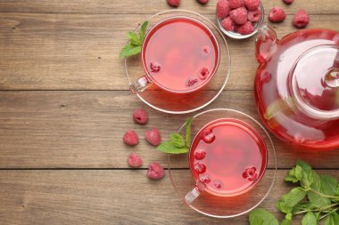 Cam fincanlarda ahududu çayı, çaydanlık, böğürtlen ve nane şekeri ahşap masada. Metin için boşluk