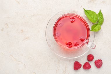 Cam fincanda ahududu çayı, açık gri masada böğürtlen ve yeşil yapraklar, düz yatak. Metin için boşluk