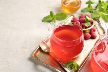 Lezzetli ahududu çayı, çaydanlık, böğürtlen, bal ve nane şekeri açık gri masada, yakın plan. Metin için boşluk