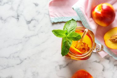 Mason kavanozunda naneli buzlu şeftali çayı ve beyaz mermer masada taze meyveler. Metin için boşluk