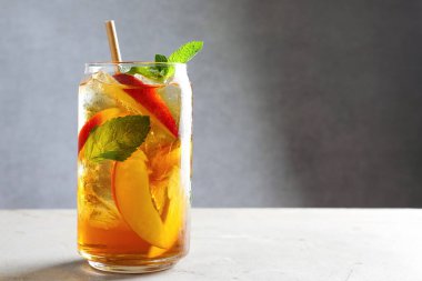 Buzlu şeftali çayını beyaz masada nane şekeriyle tazeliyorum, yakın plan. Metin için boşluk