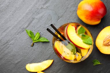 Buzlu şeftali çayı bardakta ve taze meyveler koyu masada, düz yerde. Metin için boşluk