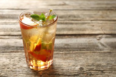 Buzlu şeftali çayını ahşap masada, cam bardakta tazeliyorum. Yakın plan. Metin için boşluk