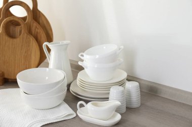 Mutfakta farklı beyaz bulaşık takımları ve tahta kesme tahtaları var.