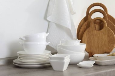 Mutfakta farklı beyaz bulaşık takımları ve tahta kesme tahtaları var.