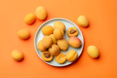 Turuncu arka planda bir sürü taze kayısı var.