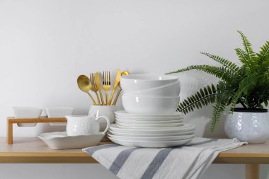 İçerideki ahşap masada farklı beyaz bulaşık takımları ve çatal bıçaklar.