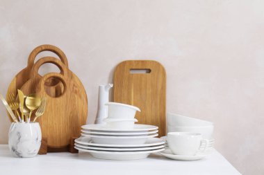 Mutfakta farklı beyaz bulaşık takımları ve tahta kesme tahtaları var.